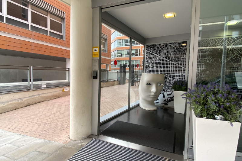 The hotel entrance is from the wide, step-free sidewalk. There are large, automatic glass doors that lead to the lobby.