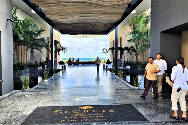 The entrance to the hotel is along a wide, step-free, marble corridor lined with plants.