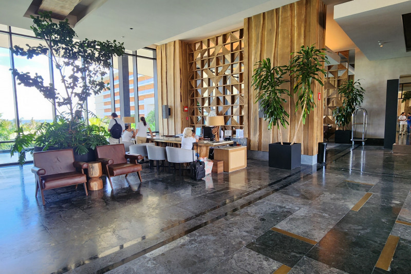 The spacious reception area has check-in desks with chairs in front of them. There are assorted chairs around the room.