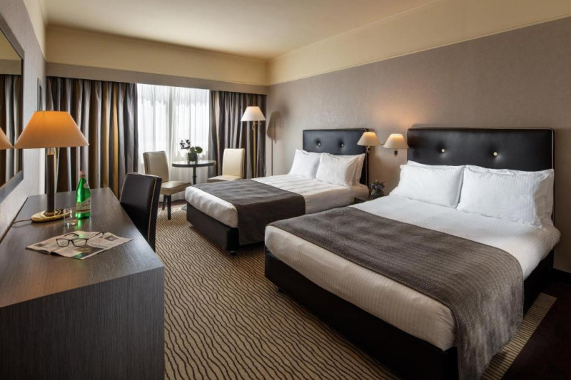 This spacious room has 2 queen-sized beds with a central nightstand. There are 3 high-back chairs, a round table and a workstation.