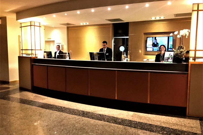 The spacious reception area has a high check-in desk with plexiglass protection screens.