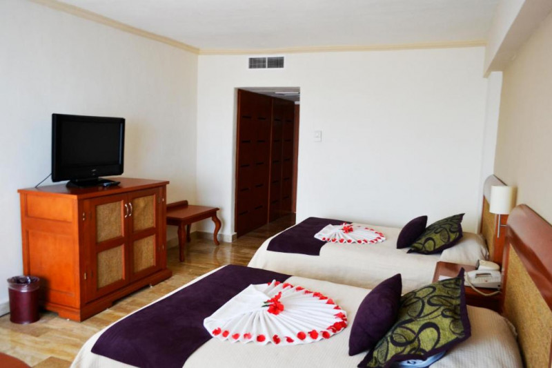 This room has twin beds with a central nightstand. Opposite the beds is a cabinet with a TV on top.