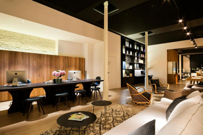 The reception area has assorted tables, chairs, and sofas. The check-in desks are low and have stools in front of them.