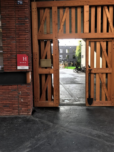 Access to the hotel is from the sidewalk. There are large wooden gates leading to an open space.