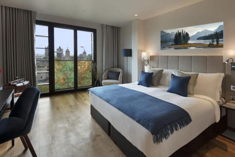 The spacious room has a king-sized bed with nightstands. There is a workstation, 2 chairs, and a bench.