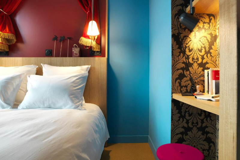 The room has 1 full-sized bed, a workstation and a stool.