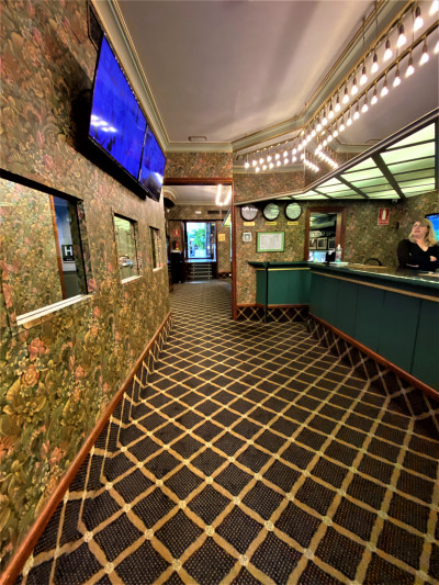 The carpeted reception area has a high check-in desk and wall-mounted screens.