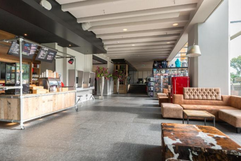 The spacious lobby has a food counter to one side of the room and sofas to another.