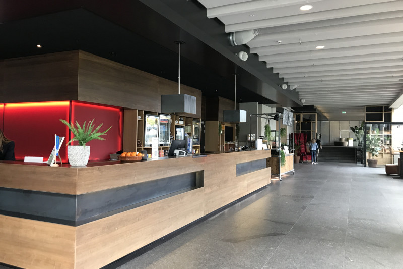 The spacious reception area has a high check-in desk. There are 6 stairs with a handrail.