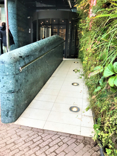 A narrow ramp with floor lights and a handrail provides step-free access to the hotel entrance.
