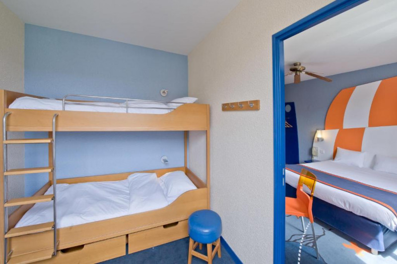 This room has 1 king-sized bed with nightstands. In a separate room there are bunk-beds with a ladder and storage space under the beds.