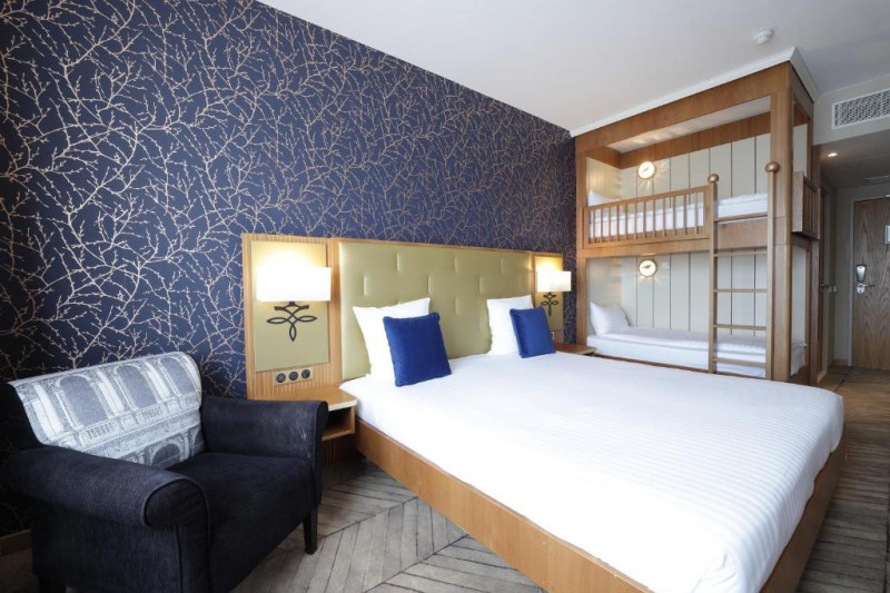 The room has 1 king-size bed with nightstands. There are wooden bunk beds with a ladder and an armchair.
