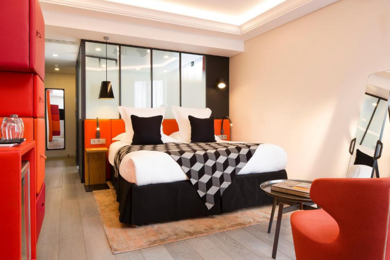 The room has 1 queen-sized bed with nightstands. There is an armchair, a coffee table, a mirror, and a mini-fridge. There is plenty of cupboard space.