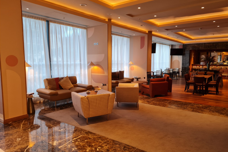The step-free bar area has assorted tables, movable chairs, and sofas. There are also 2 wall-mounted TVs.
