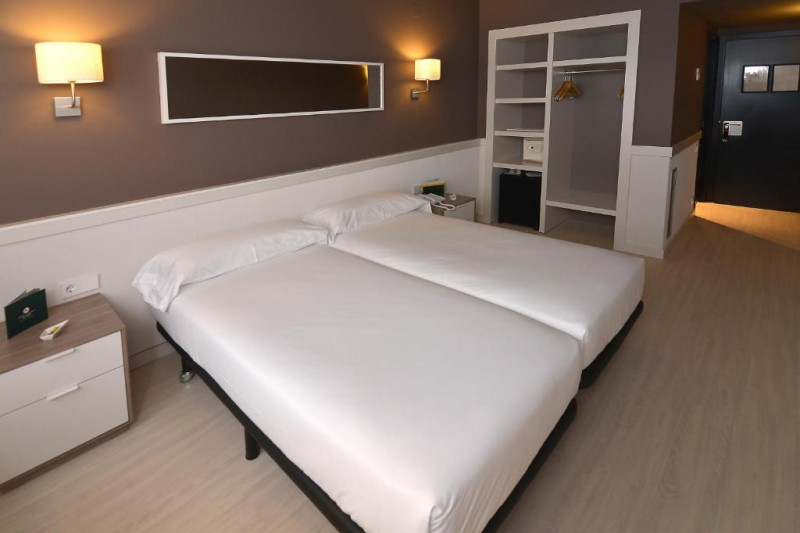 The room has twin beds with nightstands. There is a built-in closet with a safe.