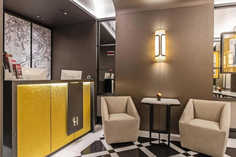 The reception area has a high check-in desk. There are 2 chairs and a small table.