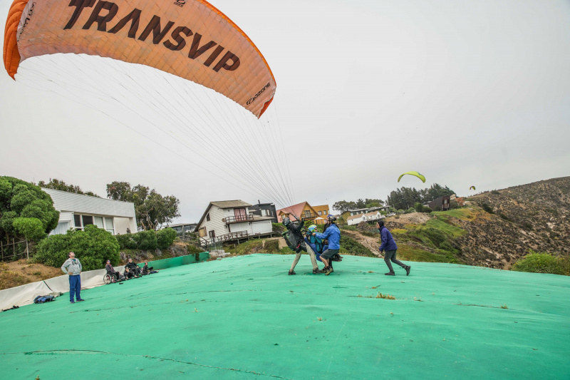 Guides assist paraglider with landing.