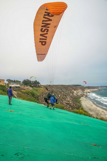 Guides assist paraglider with landing.