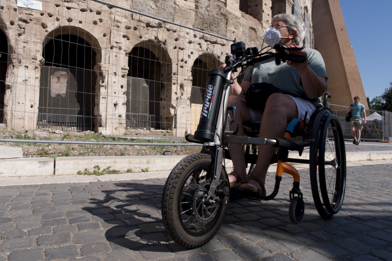 Tourist on power wheelchair visits the Via Fori Imperiali