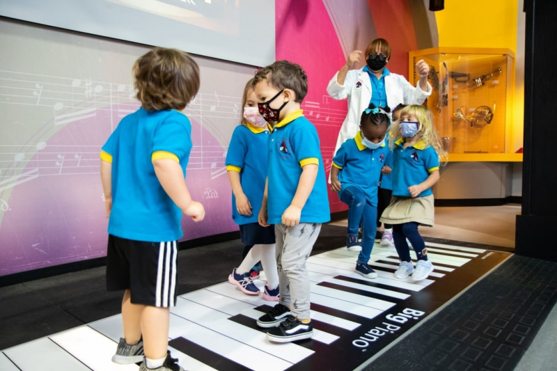 Children dancing on a giant piano keyboard on the ground.
