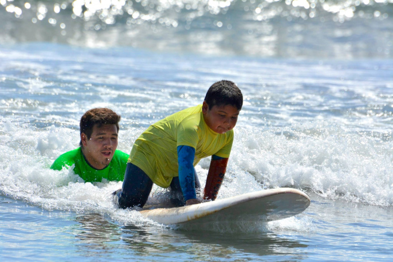 A boy enjoying surf lessons with the help of an instructor.
